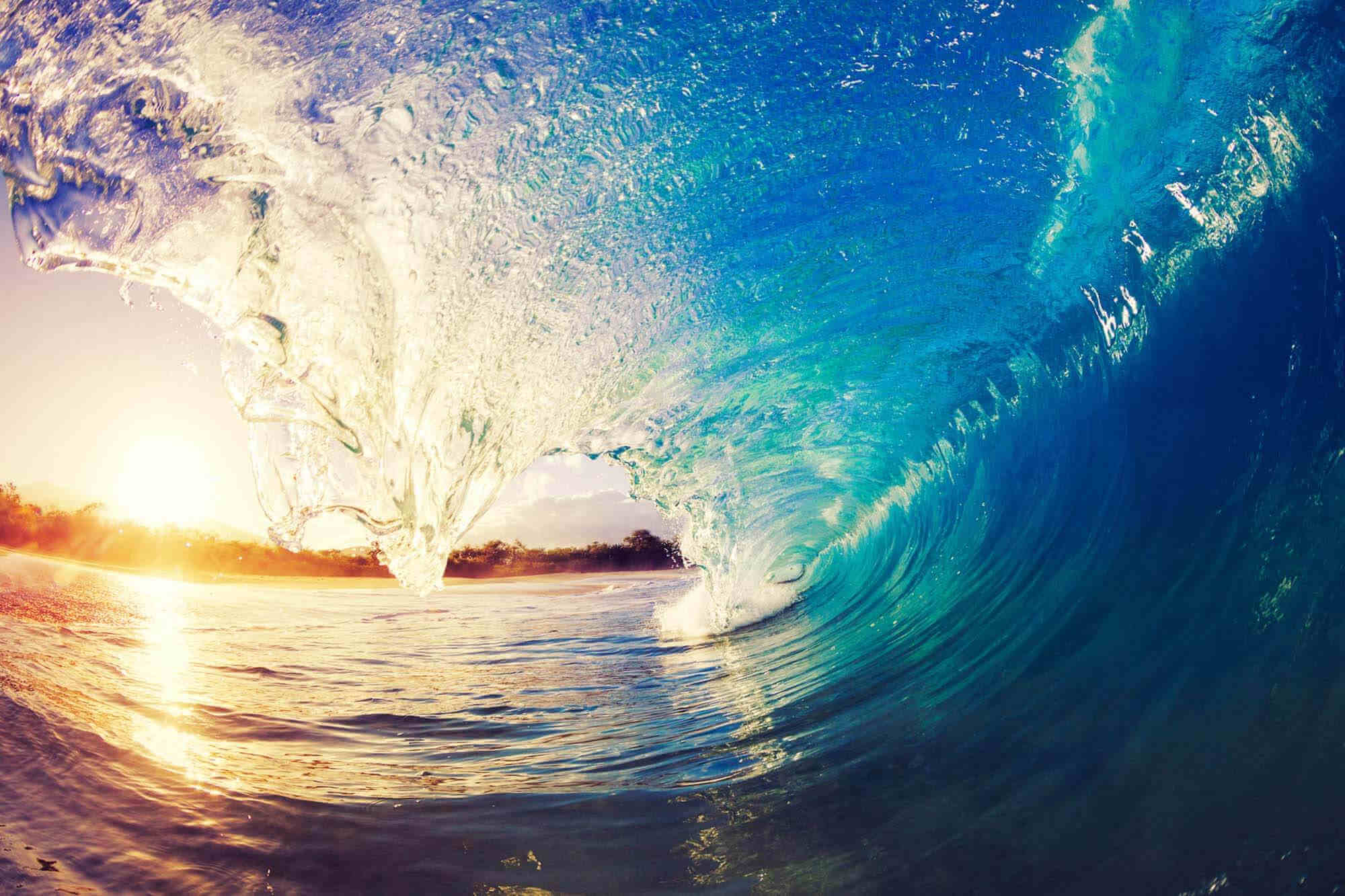 View from inside a cresting wave, facing a sunset
